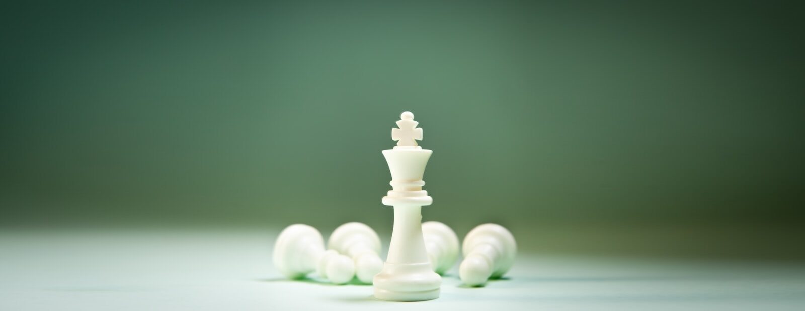 A white king chess piece stands tall over fallen pieces.